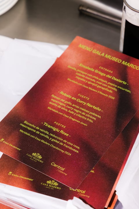 Red menu card with Spanish text and gold lettering on white table at restaurant
